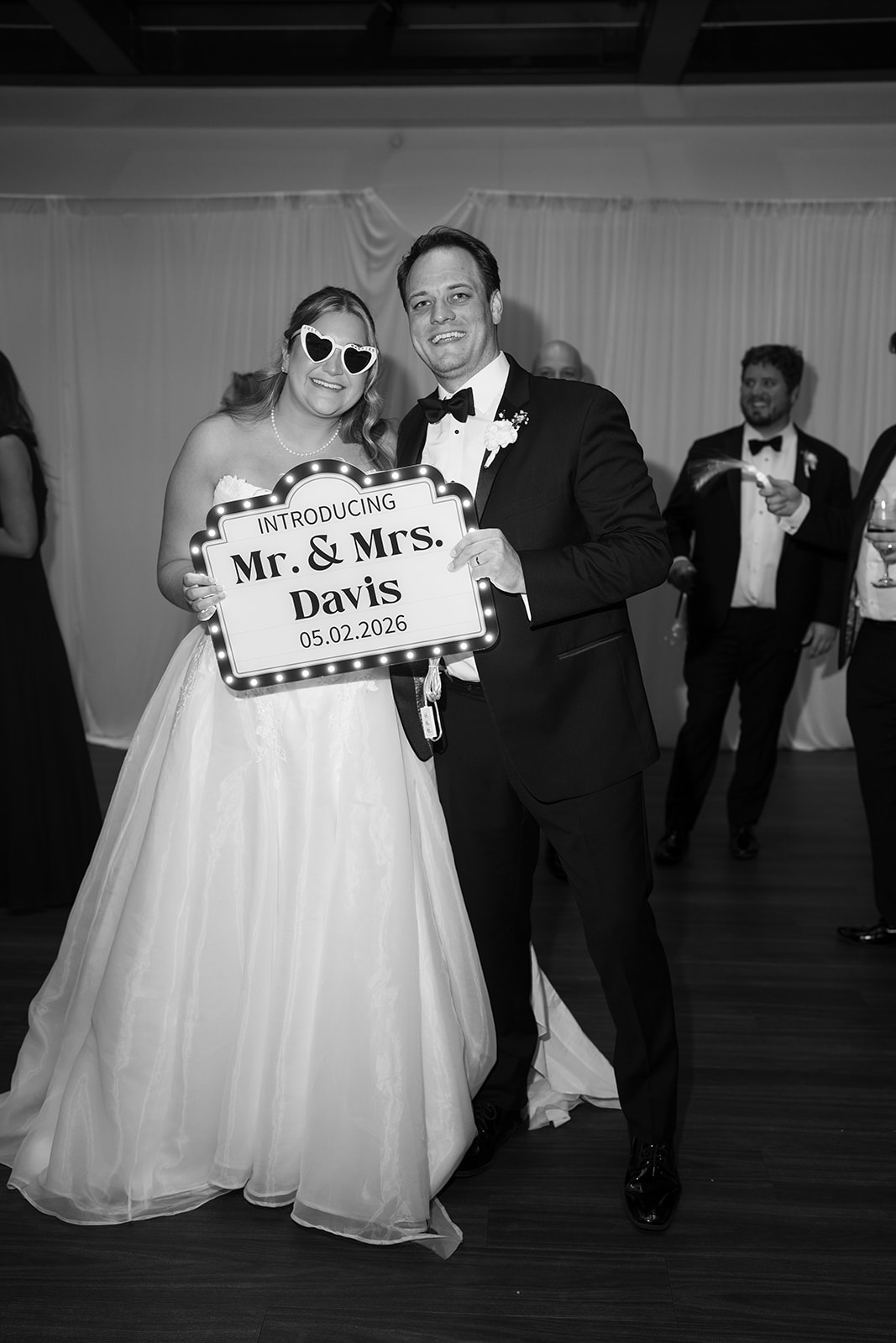 Ben and Hannalee holding a Mr. and Mrs. Davis sign at the reception