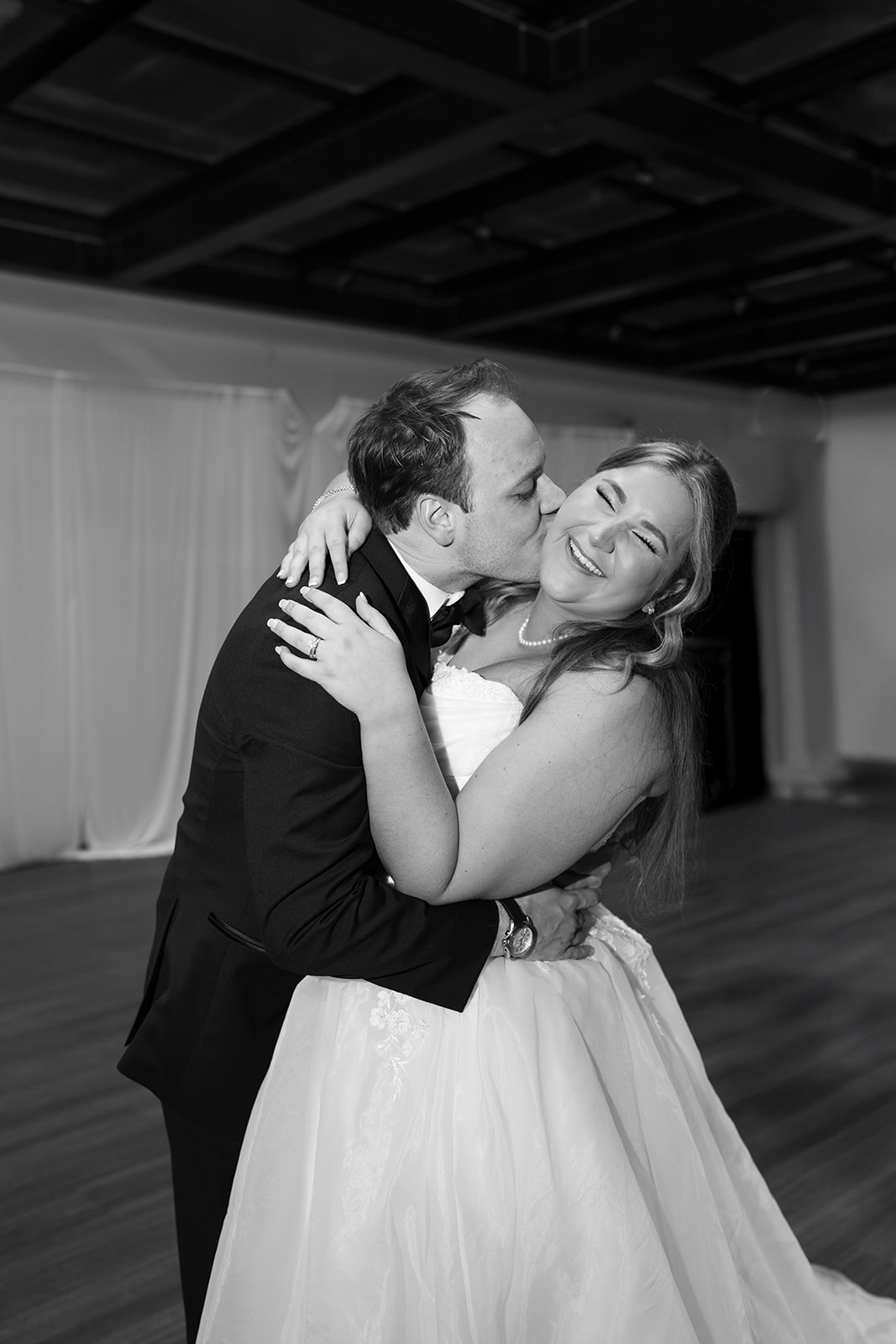 Black-and-white photograph of Ben kissing Hannalee during the reception