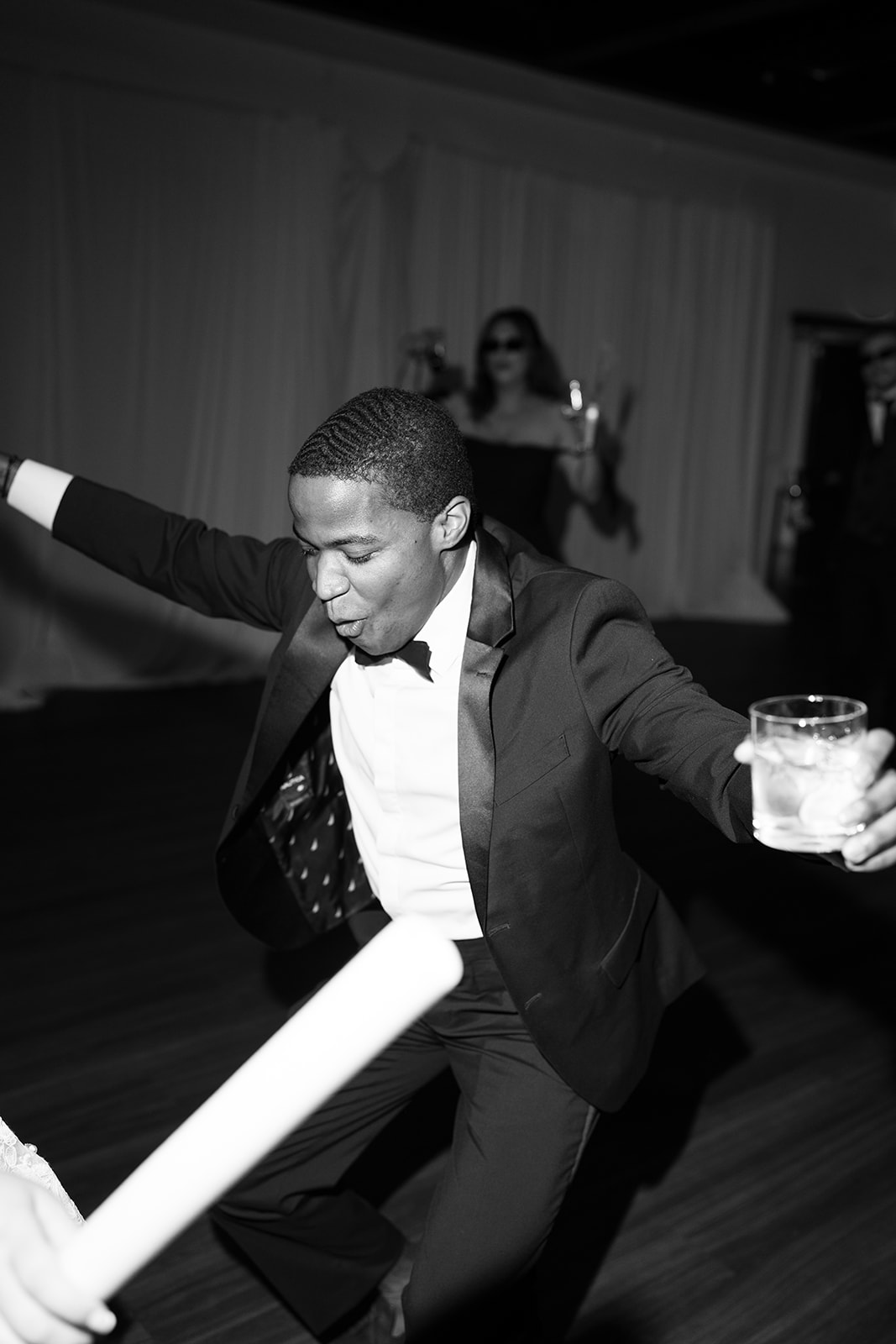 Black-and-white dance-floor candid with a guest holding a glow stick