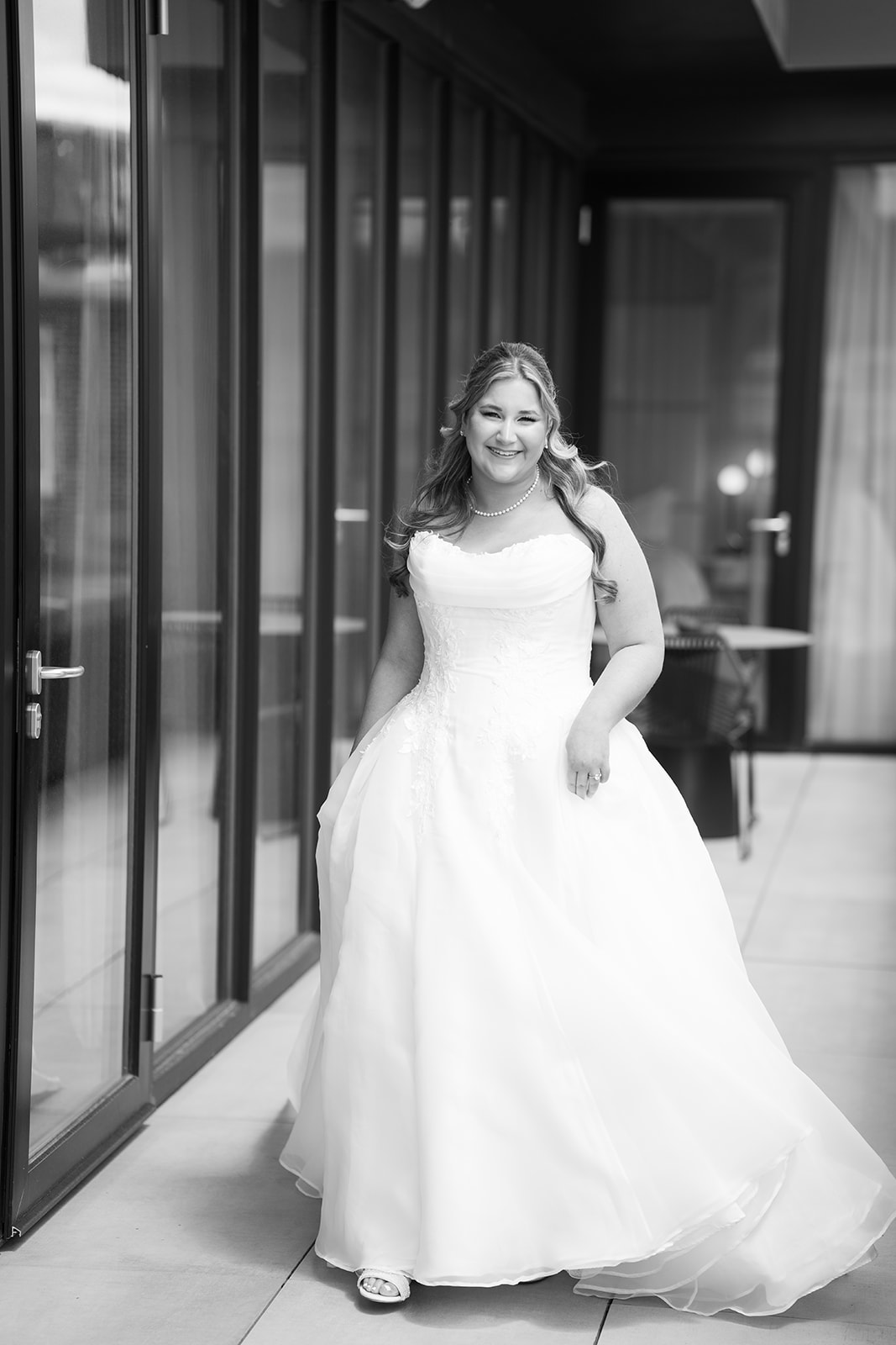 Black-and-white bridal portrait of Hannalee beside glass doors