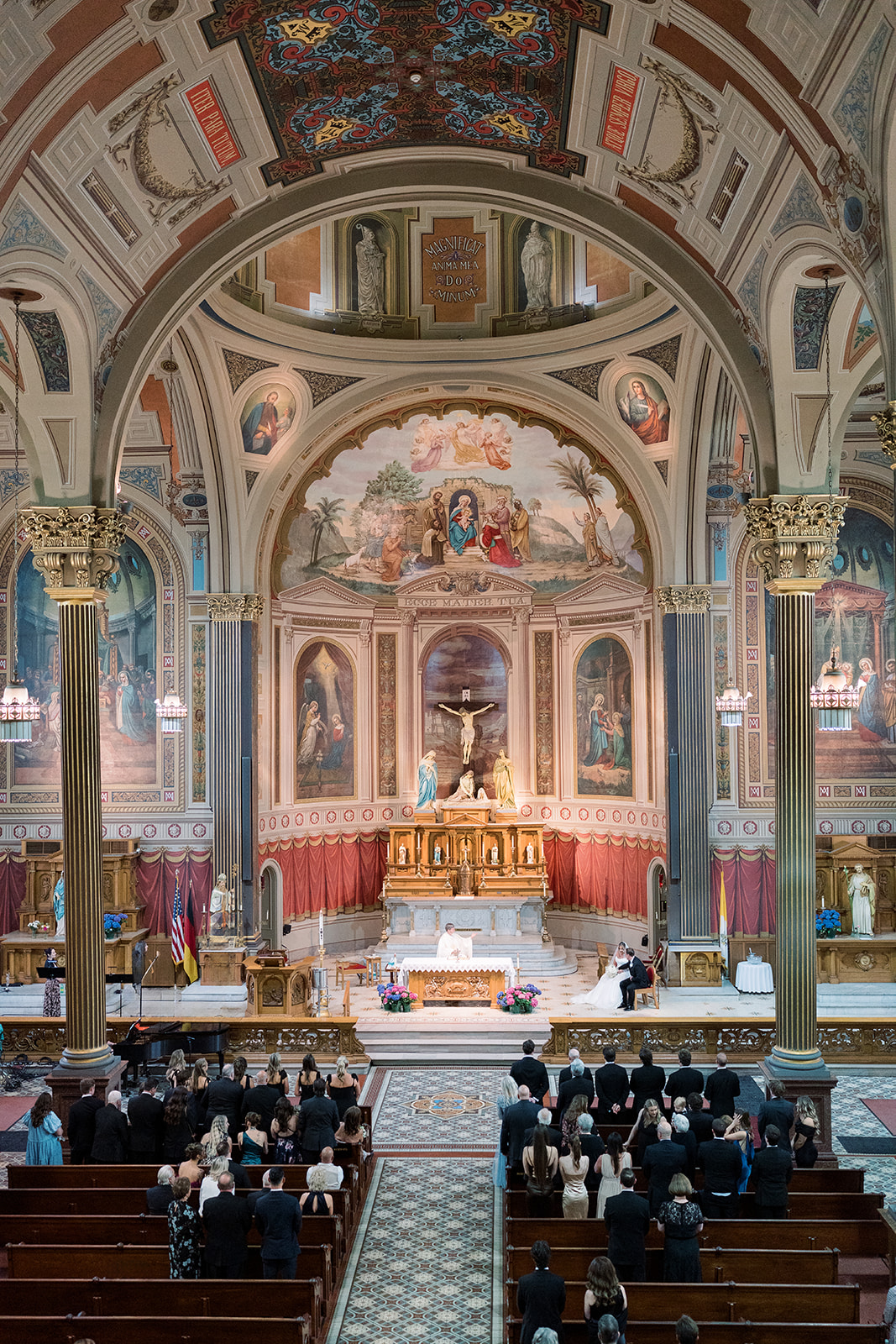Wide ceremony view framed by the painted interior of Mother of God Church