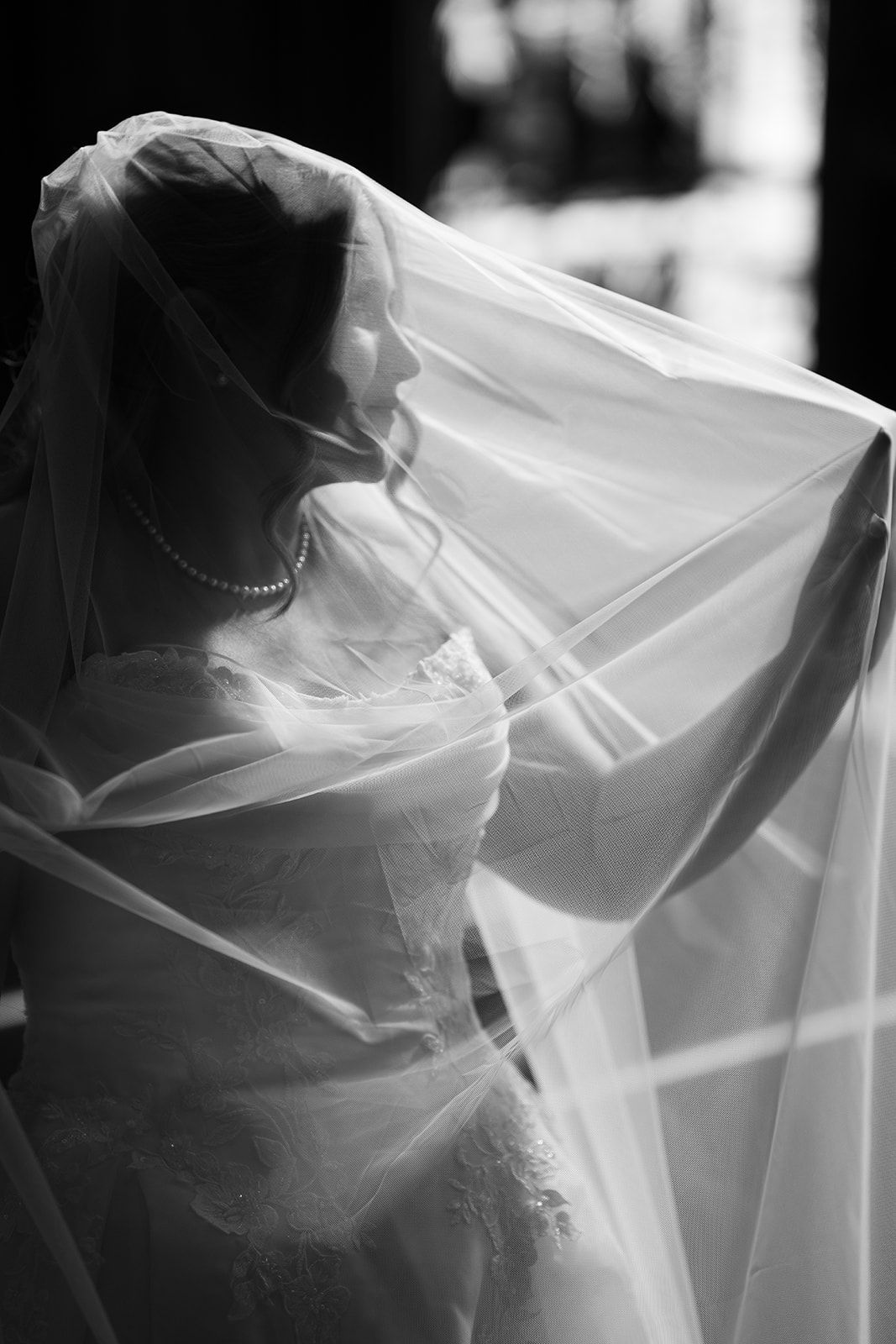 Black-and-white portrait of Hannalee lifting her veil