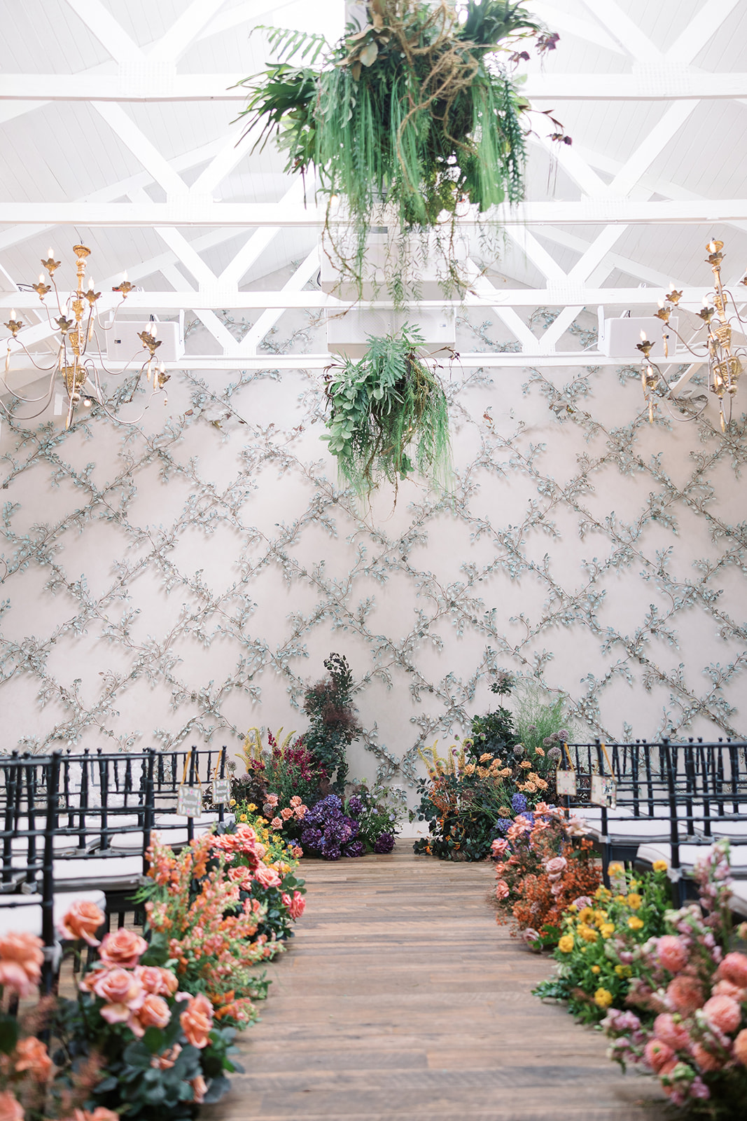 Colorful flower-lined ceremony aisle beneath the wirework garden trellis at Terrain Gardens at DelVal