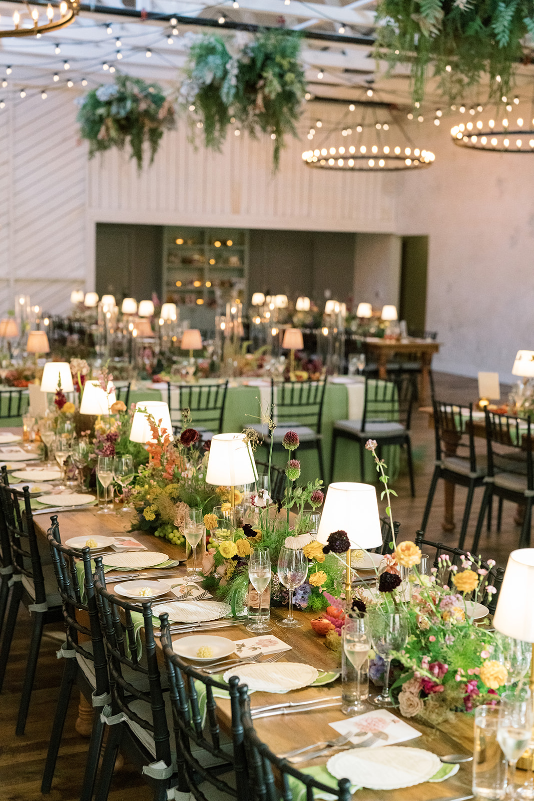 Long reception table filled with flowers, fruit and small lamps at Terrain Gardens at DelVal