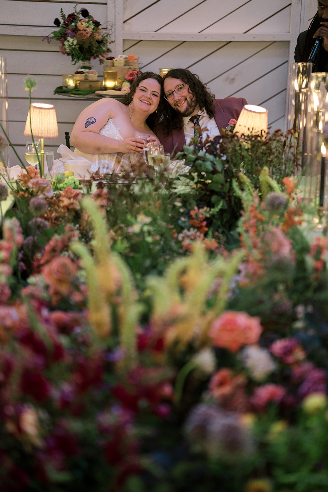 Wedding guests sharing a candid moment across the floral reception tables