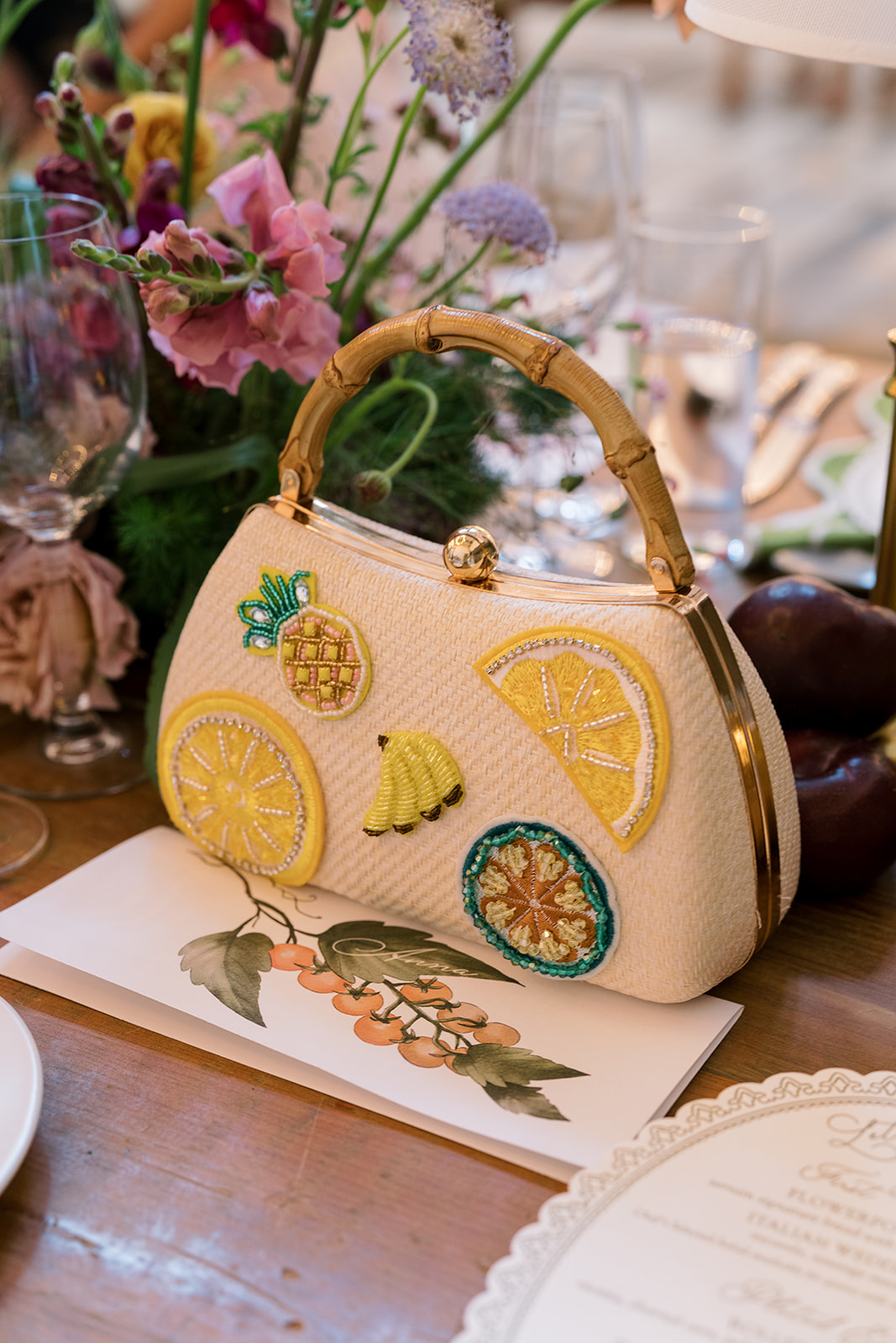 Decorative fruit-themed handbag beside the reception flowers