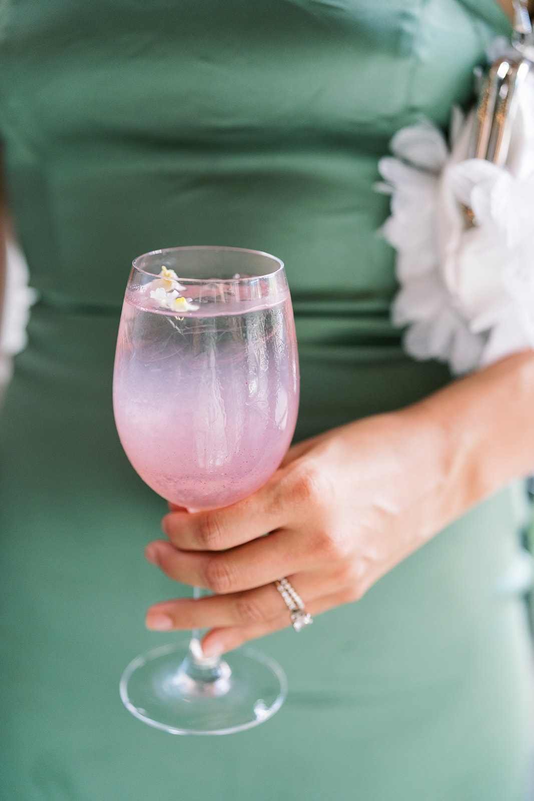 Guest holding a pink signature drink against a green table setting