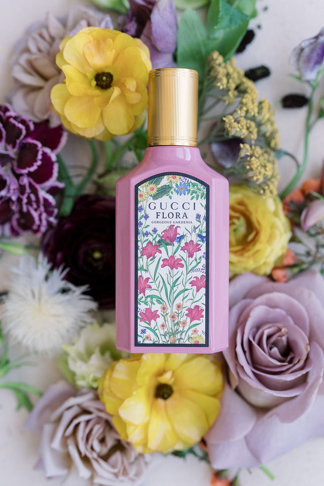 Perfume bottle surrounded by wedding flowers and stationery