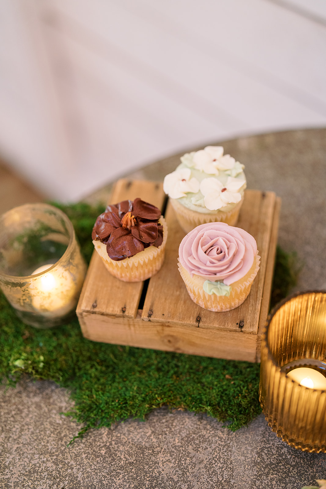 Mini desserts arranged on a wooden display beside votive candles