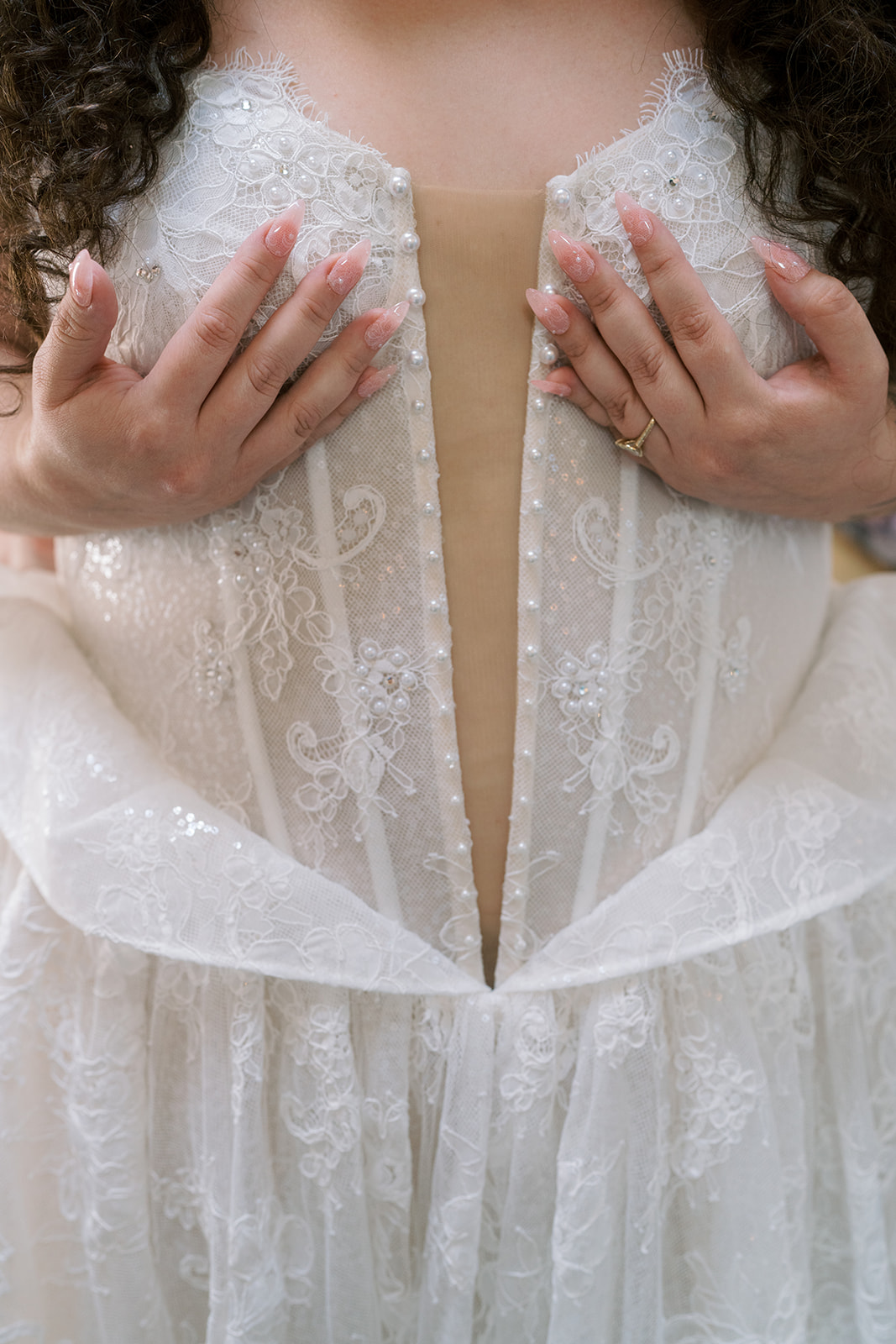 Close detail of the bride's lace bodice and hands