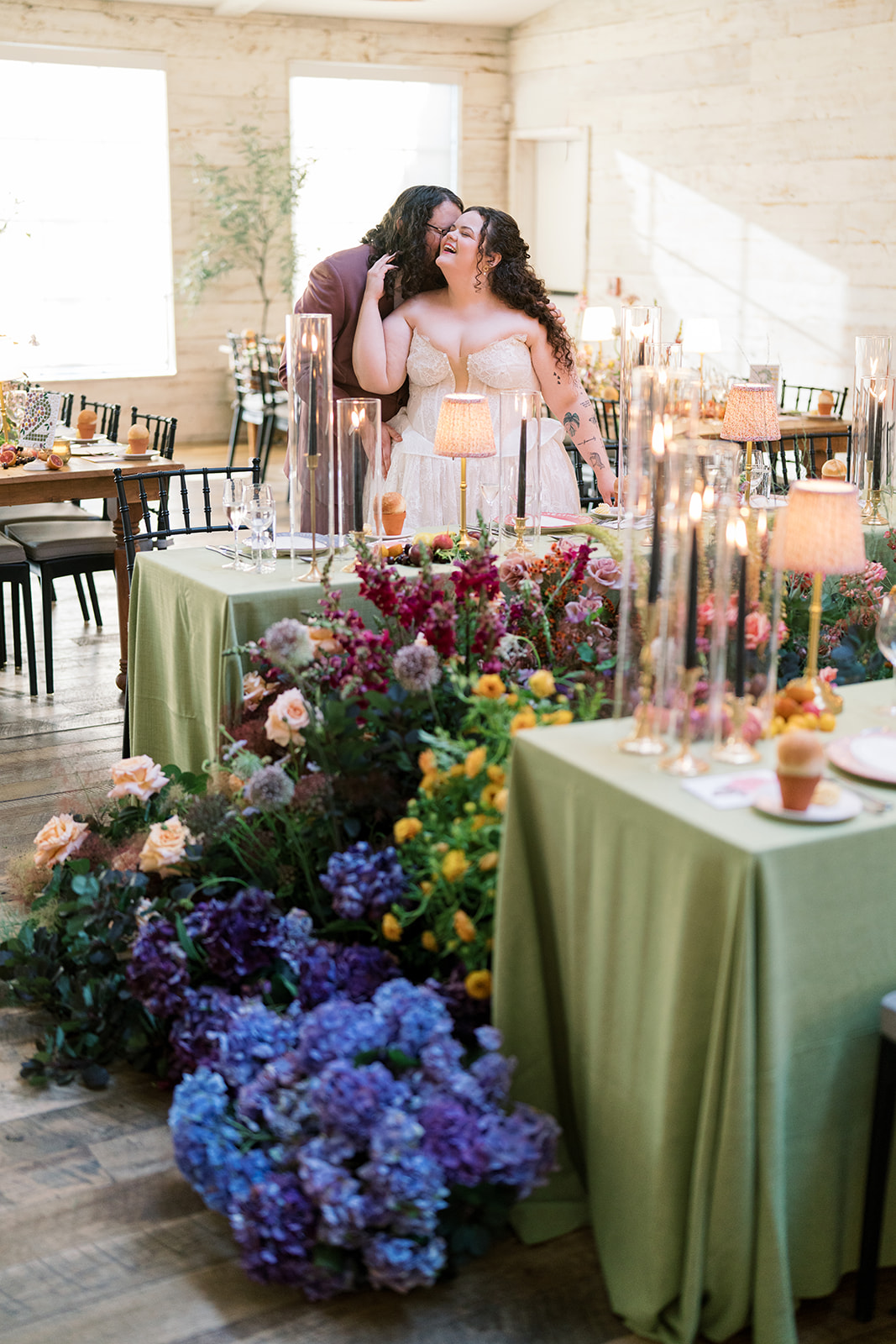 Bride leaning beside a reception table overflowing with flowers