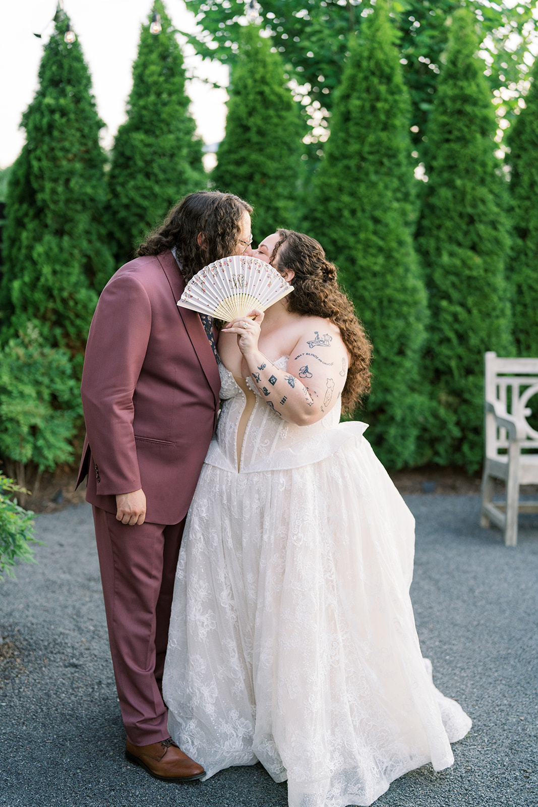Jeff and Breanna kissing beside tall greenery outside the venue