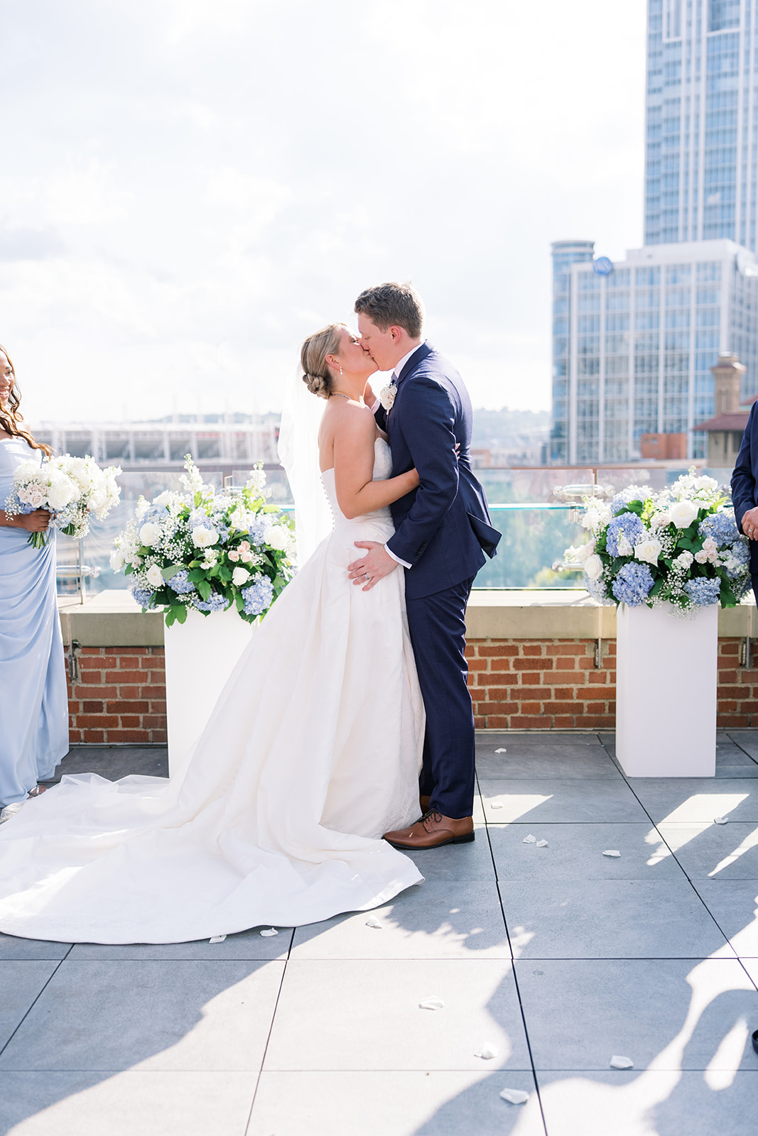 Joey and Caroline kissing on the rooftop at Vista at Lytle Park with the Cincinnati skyline behind them