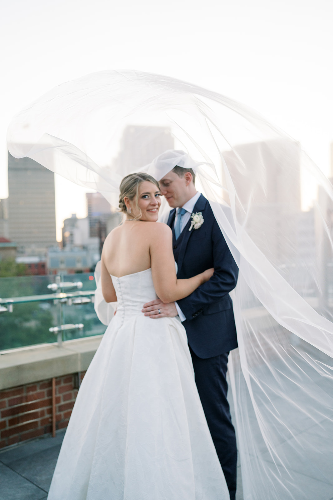 Joey and Caroline under Caroline's veil with the Cincinnati skyline behind them