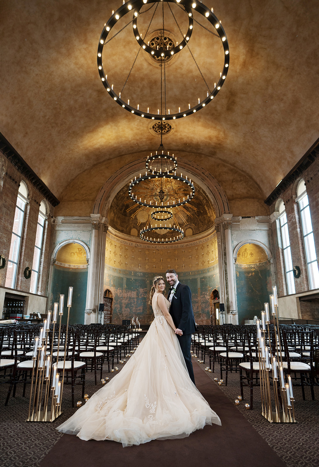 Courtney standing in the candlelit ceremony space at The Monastery Event Center