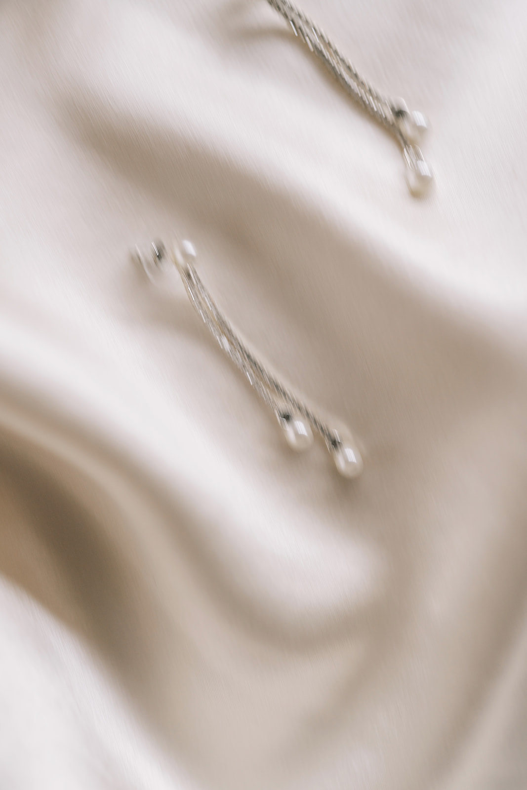 Bridal jewelry details arranged on ivory satin before the wedding
