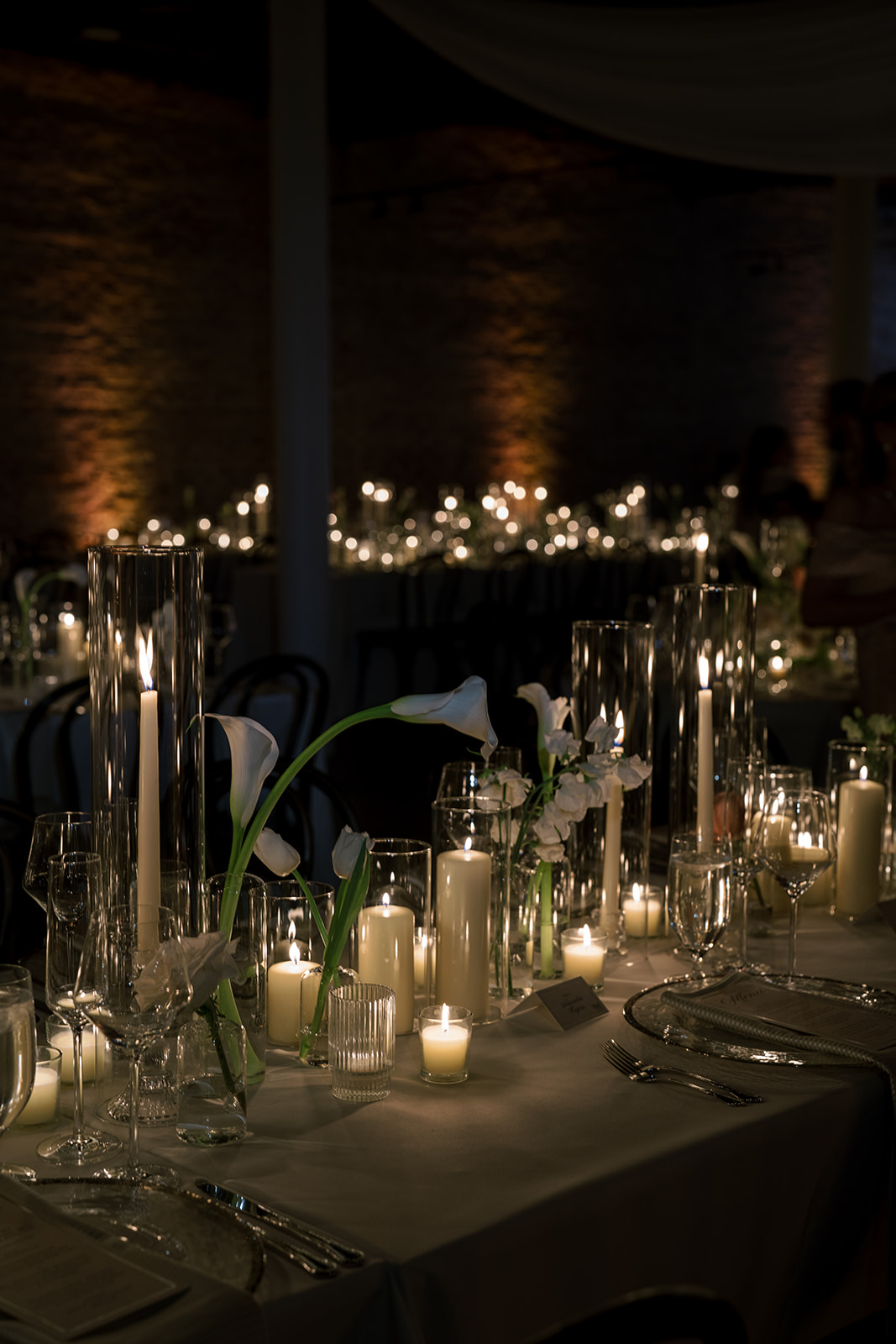 Long reception table glowing with candles, glassware and flowers