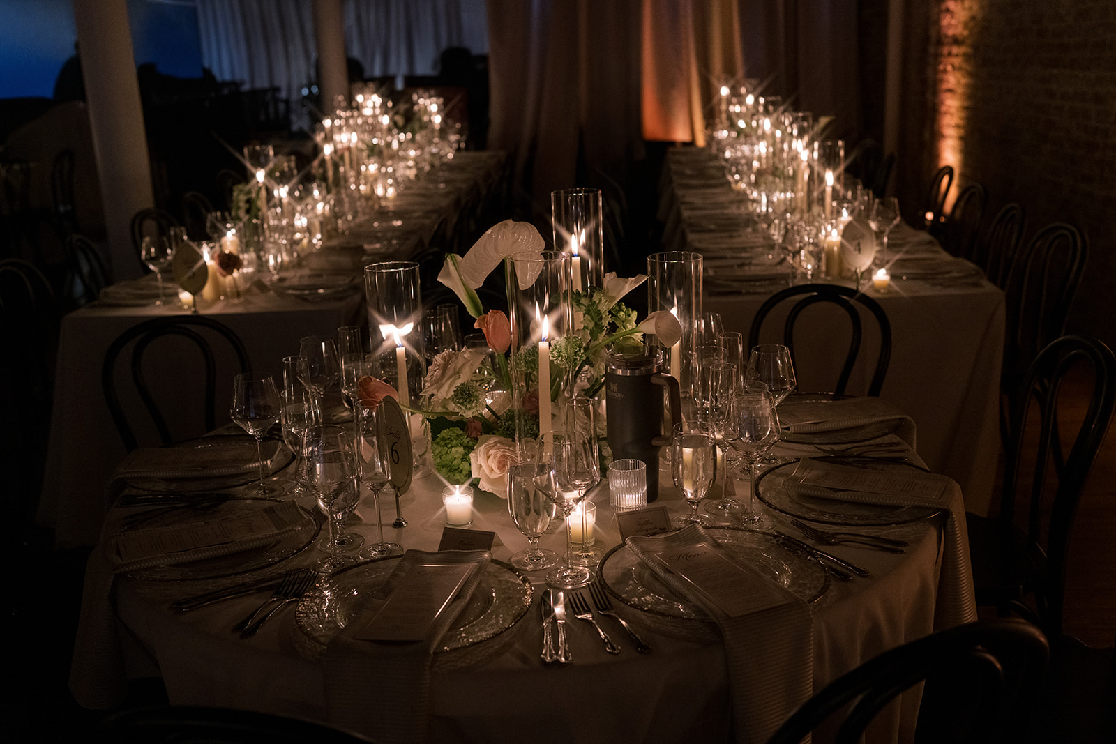 Round reception table set with flowers and candles in the darkened room