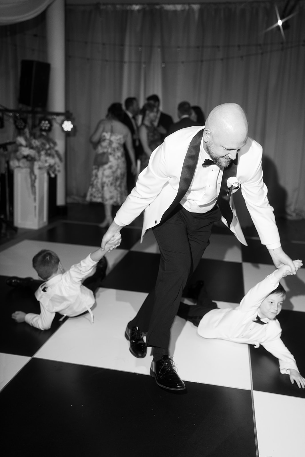 Kevin dancing with young guests on the black-and-white reception floor