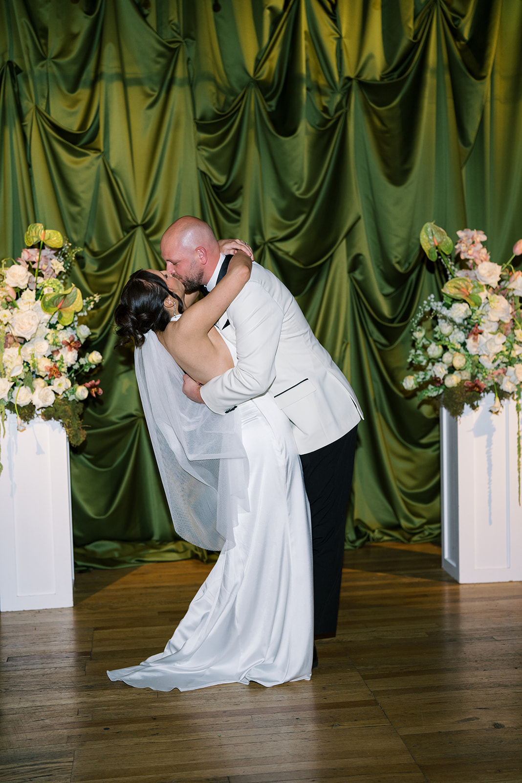 Meghan and Kevin kissing at the green draped ceremony setting