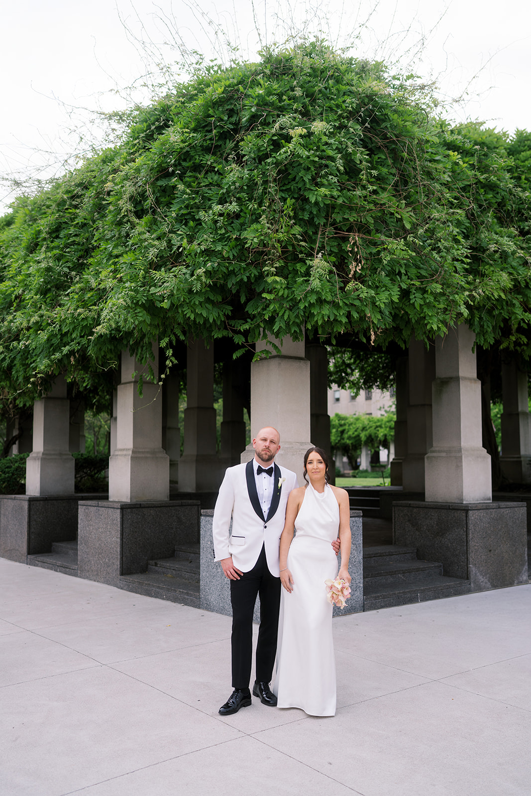 Meghan and Kevin standing beneath an ivy-covered pergola in downtown Cincinnati