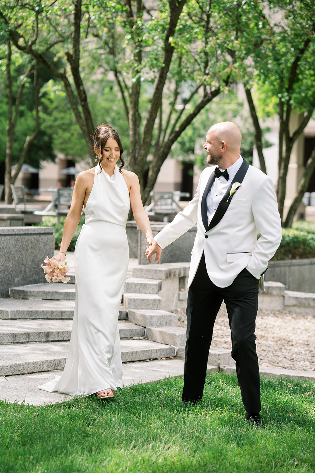 Meghan and Kevin walking hand in hand beneath trees in downtown Cincinnati