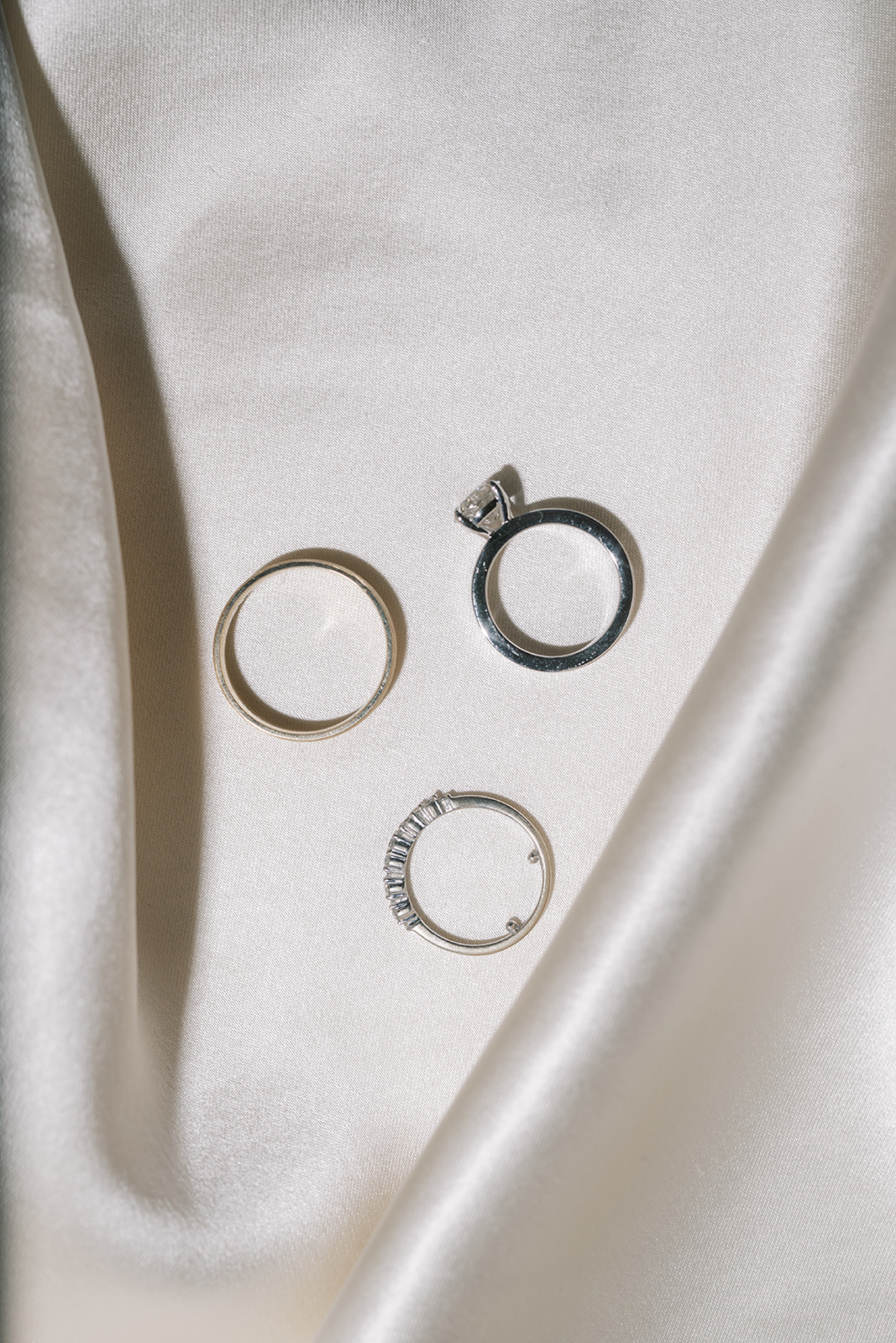 Meghan and Kevin's wedding rings arranged on ivory satin