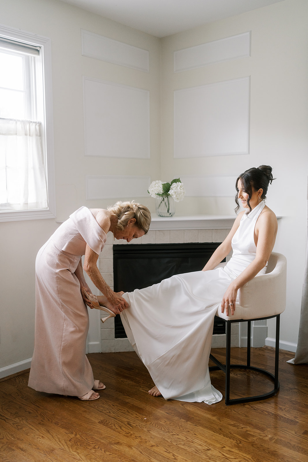 A wedding-day helper adjusting Meghan's gown while she gets ready