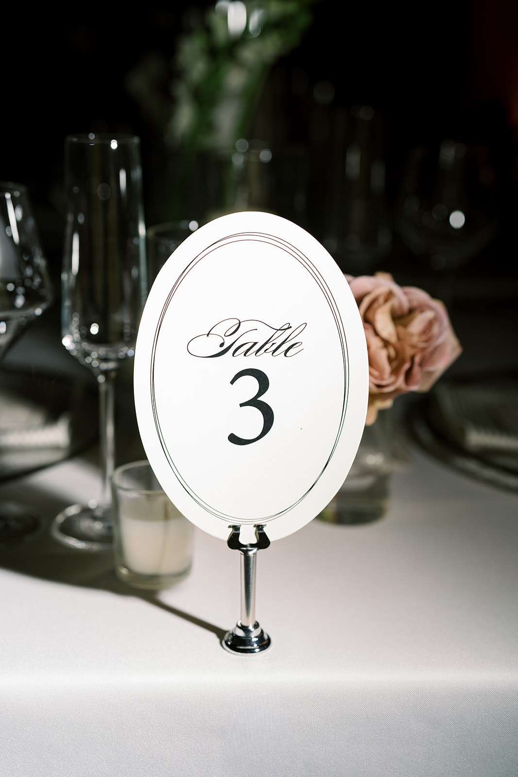 Table number three displayed among glassware and candlelight at the reception