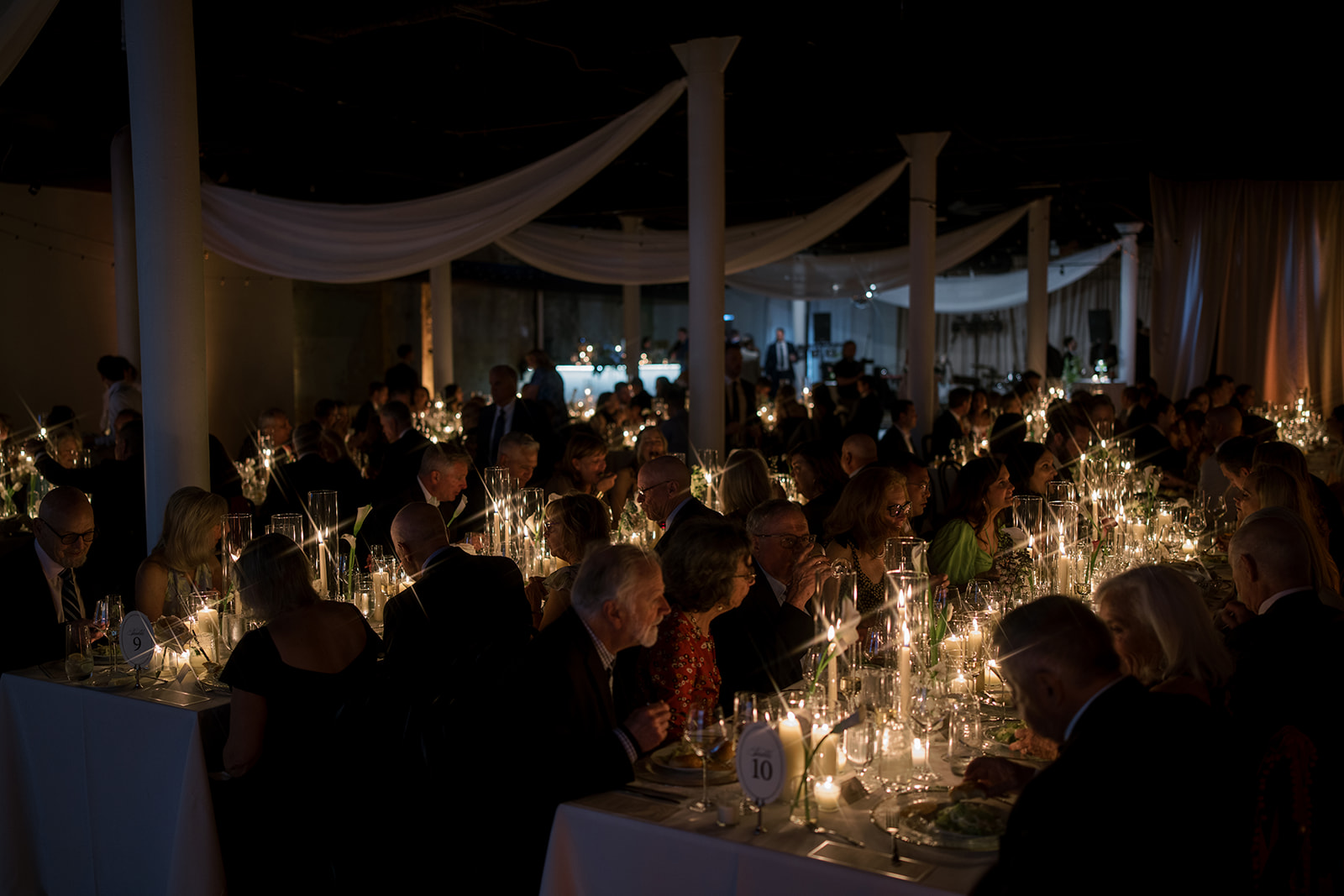 Guests seated at long candlelit dinner tables inside The Spot on West Fifth