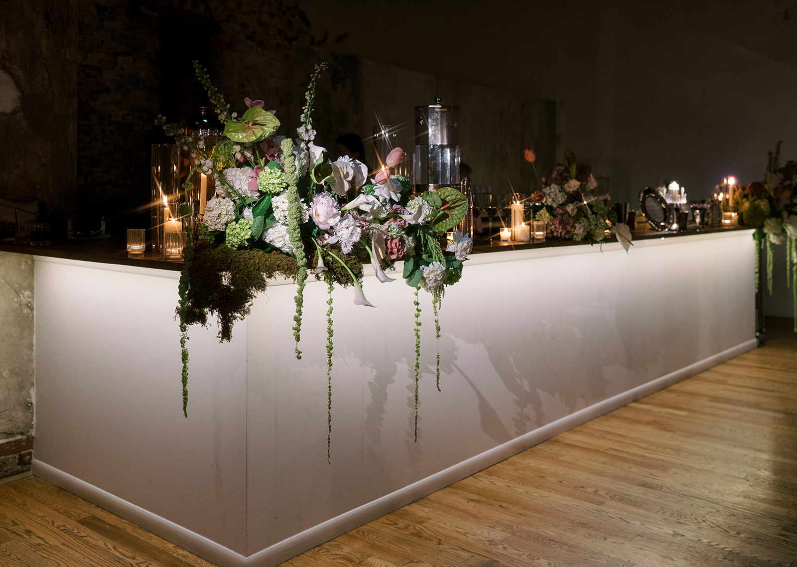 Illuminated reception bar topped with pink, white and green flowers