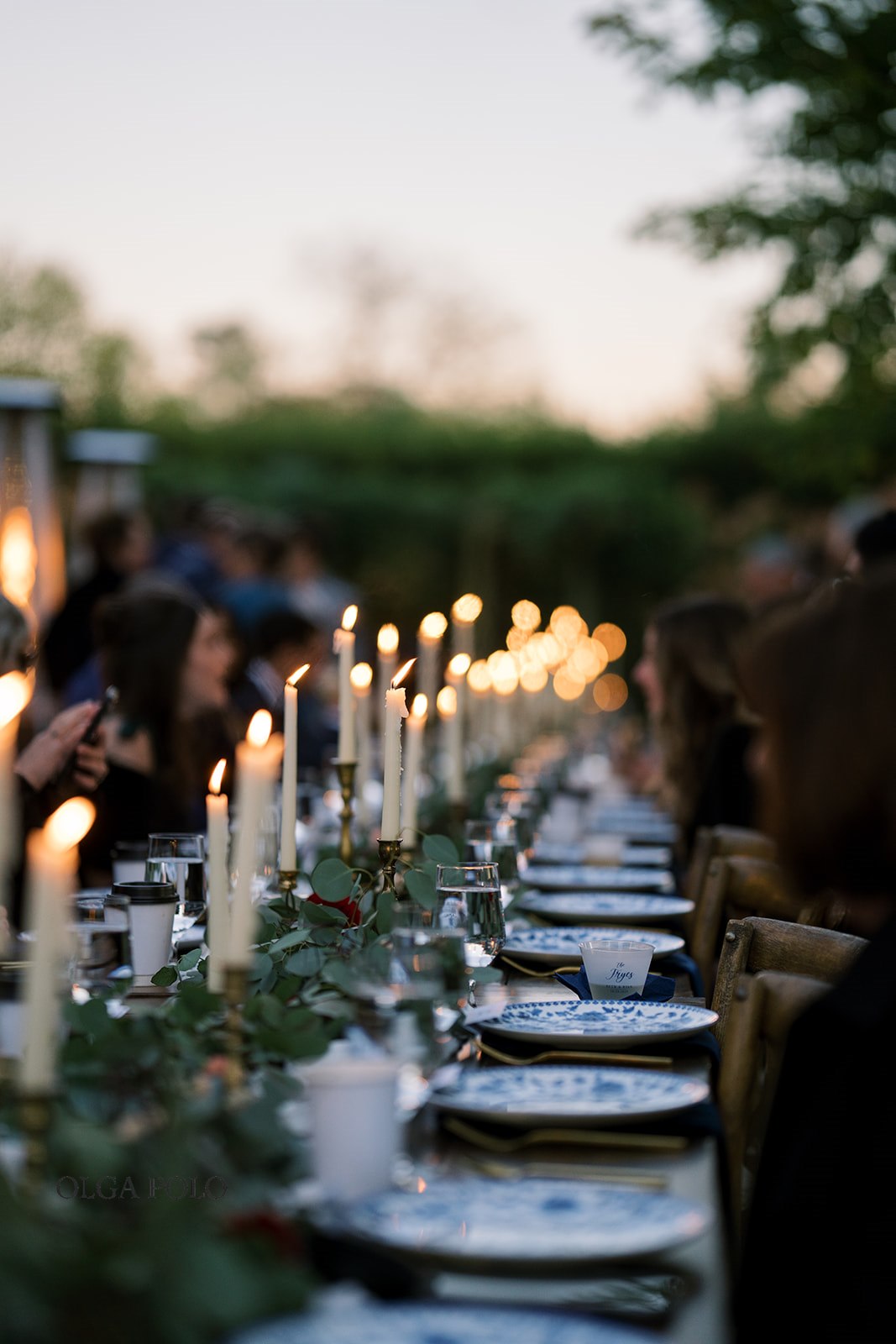 Candlelit place settings and greenery along the long outdoor wedding table