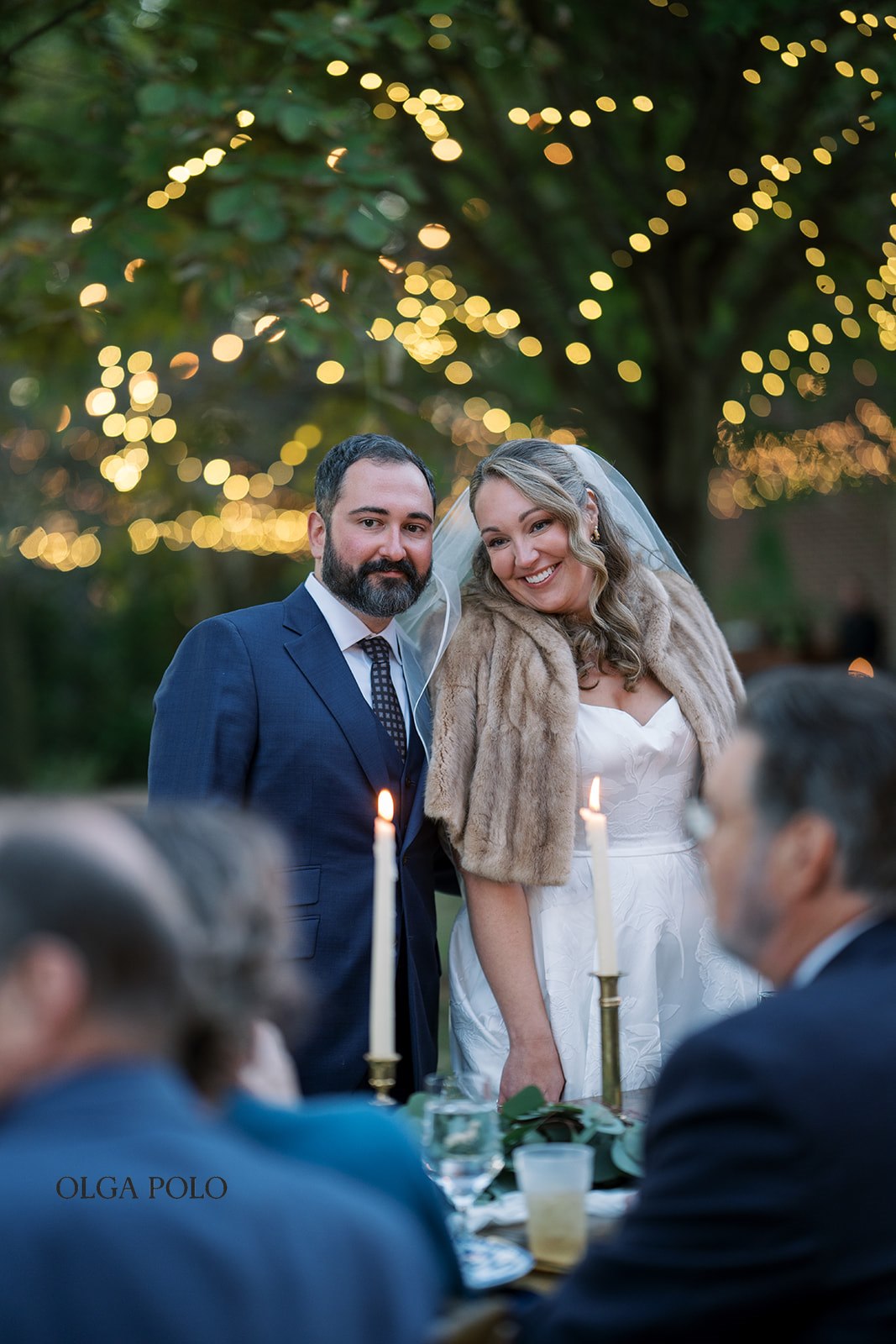 Ryan and Beth seated together at the candlelit outdoor reception table