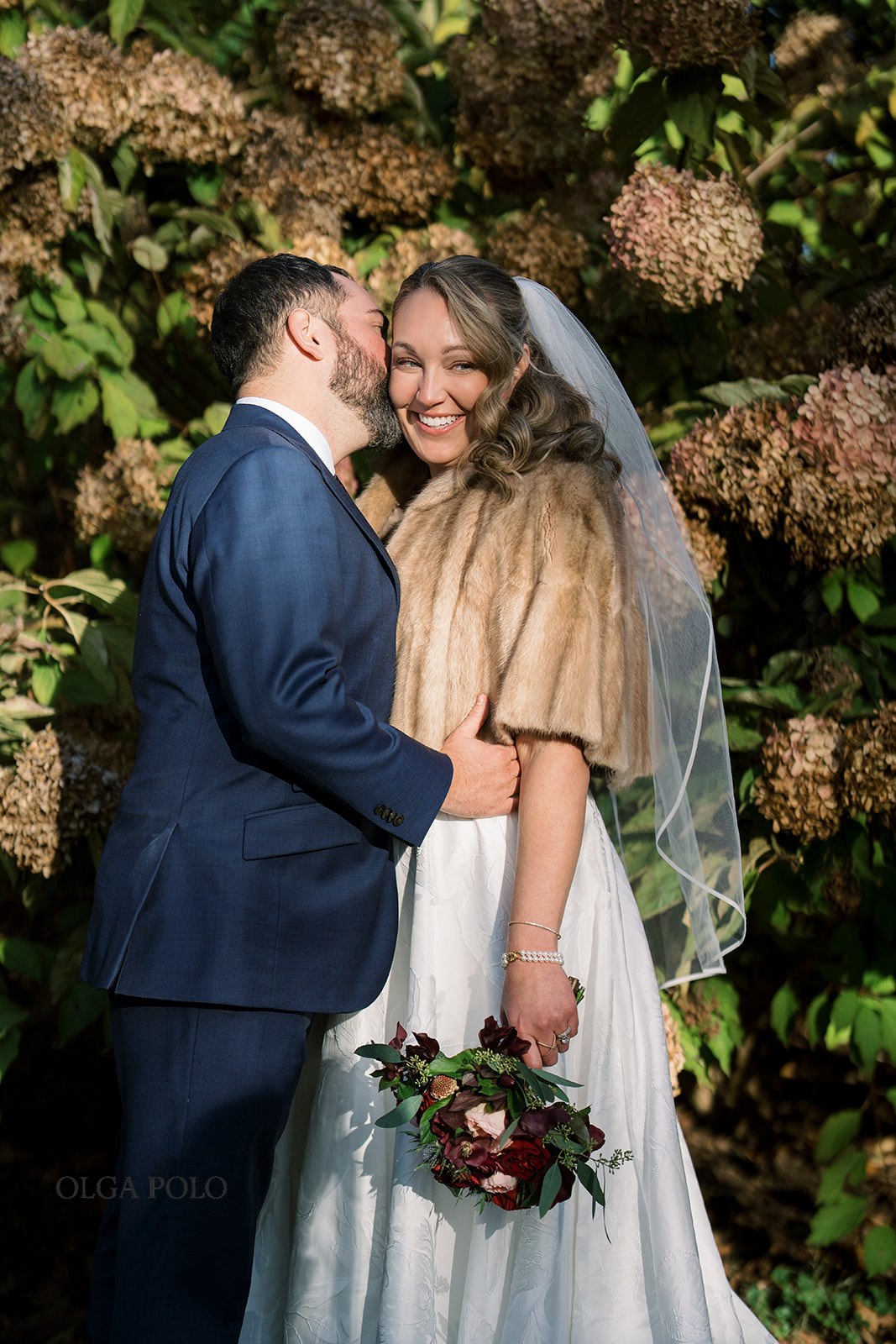 Ryan and Beth embracing near hydrangeas in soft evening light