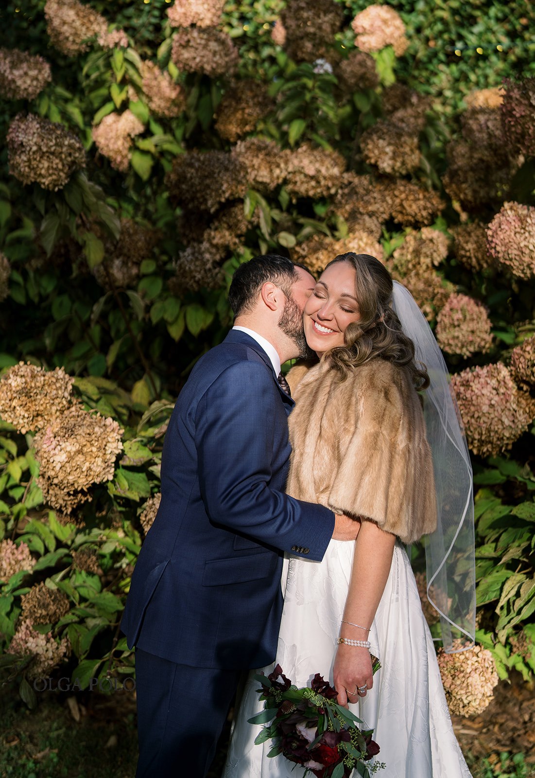 Ryan and Beth embracing in front of autumn hydrangeas