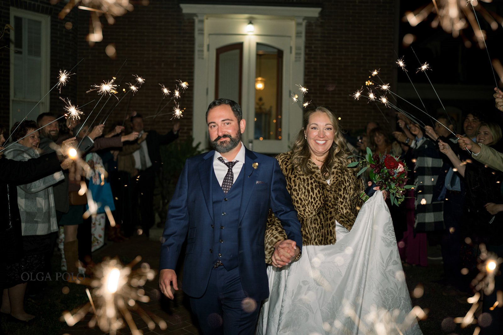 Ryan and Beth walking through a sparkler send-off at night